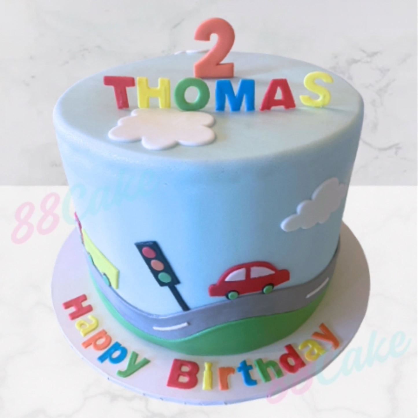 Children's birthday cake with colorful traffic-themed decorations and 'Happy Birthday' text.