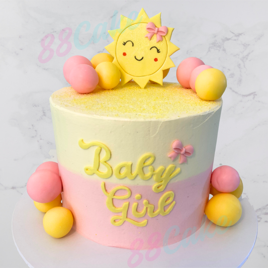 Pink and yellow baby shower cake with a cute sub and decorative balls with baby girl on the front