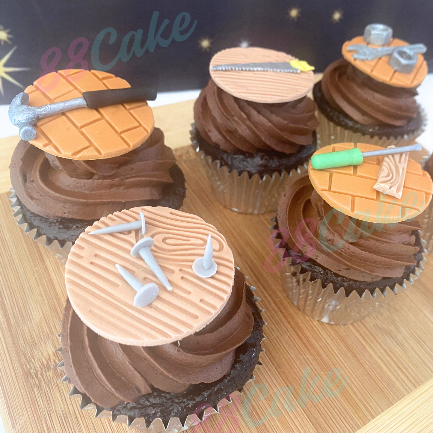 Cupcakes decorated with fondant wooden and brick look toppers with tools, branded '88Cake’