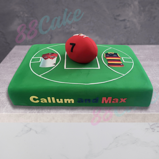 Soccer field cake decorated with two teams and a red soccer ball