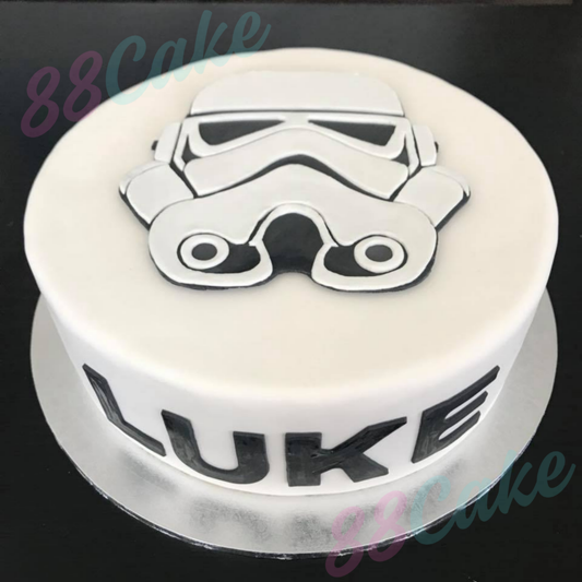 Round cake with a stormtrooper design and the name 'Luke' on a black background.