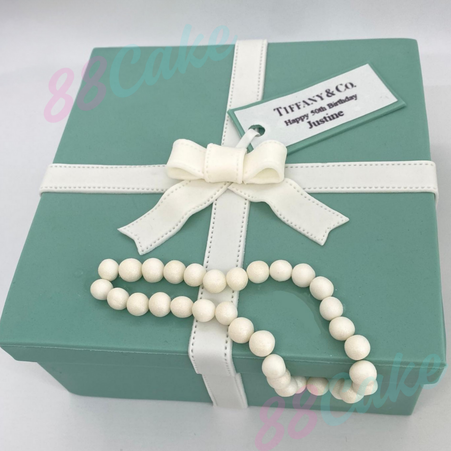 Tiffany & Co. box shaped cake with a white bow and pearl necklace